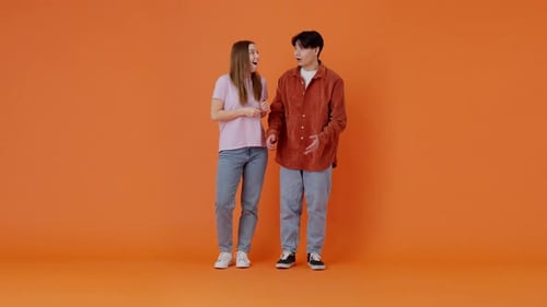 Excited Young Adults Cheering on an Orange Background