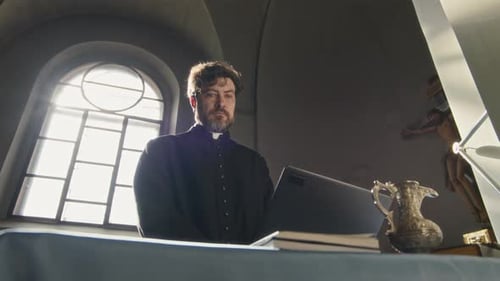 Catholic Clergyman Working on Computer in Church