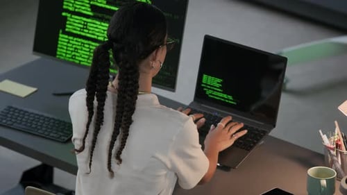 Joven programadora trabajando en la codificación de programas en el escritorio de la oficina nocturna