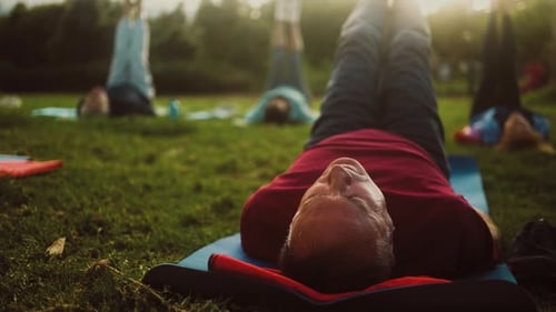 Close up mature man doing workout activity with a group of friends in a public park
