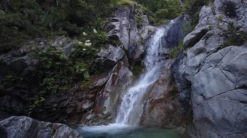 Waterfall flowing gently over rocky terrain surrounded by lush greenery and nature