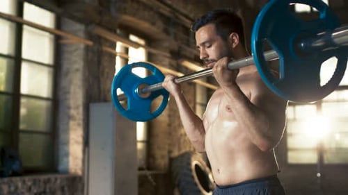 Muscular Shirtless Man Lifts Heavy Barbell with Effort, Does Biceps Curls/ Bodybuilding Exercise in