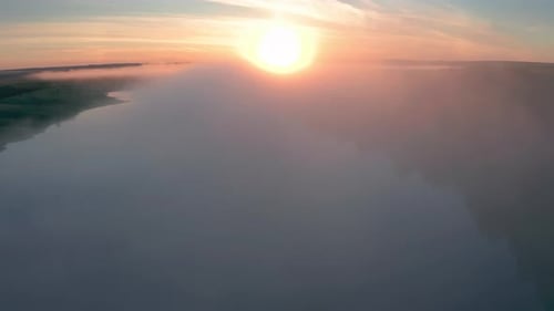 Aerial view of the summer fog forming over the lake during sunrise