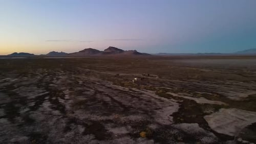 Herd of horses on the desert winter landscape at sunset with rugged mountains in the background - ae