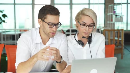 Coworkers Reviewing Laptop in Bright Office