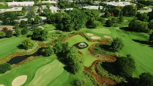 Aerial drone rotating shot over a beautiful golf club covered with green vegetation and ponds with f