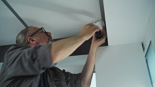 Professional Male Installer Screws Security Camera in Office Room Adjusts the Angle