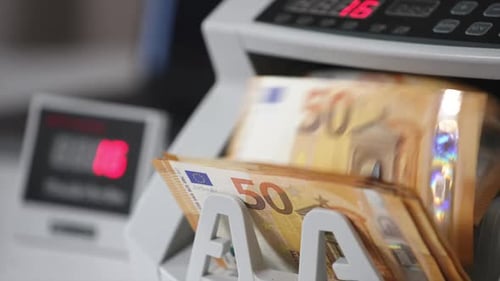 Orangefarbene fünfzig-Euro-Banknoten drehen sich schnell in der Geldzählmaschine.