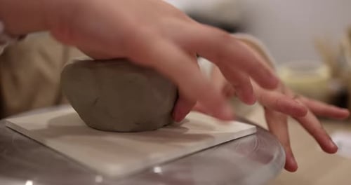 Child shaping clay bowl with hands at workshop