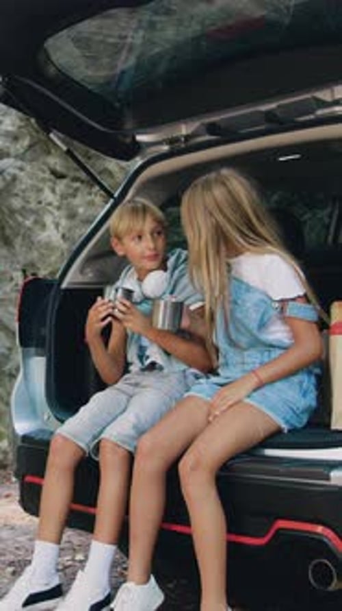 Smiling Two Teen Children Have Picnic in Forest They Have a Stop with Car Sitting in the Trunk and