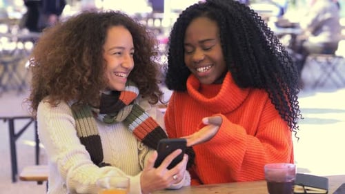 Two Friends Laughing at Smartphone Outdoors
