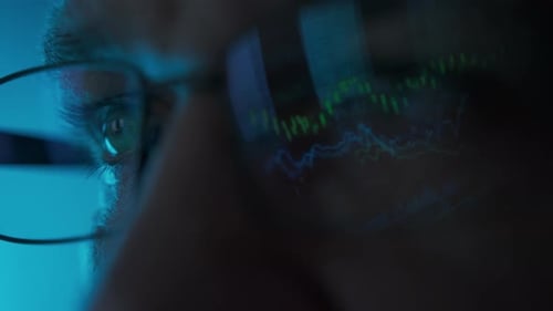 Stock Market Trader Working Investment Charts Graphs Ticker Diagrams Projected on Reflecting in