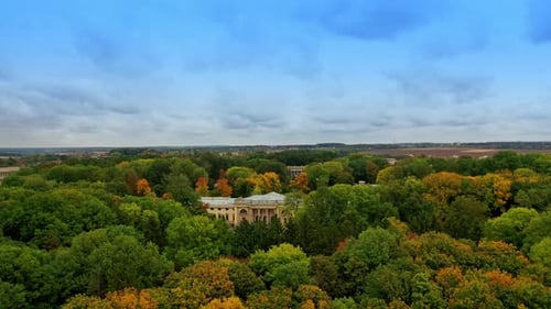 High trees park with beautiful palace in the middle. Farmlands at backdrop.