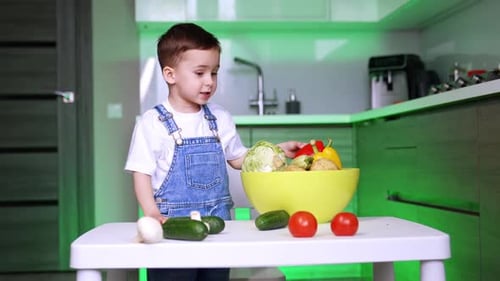 Cute Child with Colorful Vegetables in Kitchen
