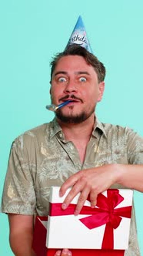 Man Wearing Party Hat Happily Receiving Longawaited Birthday Gift Showing Excitement and Gratitude
