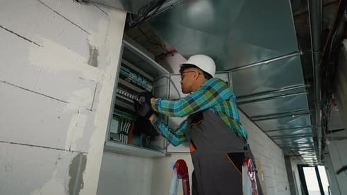 Electrician Installing Cables and Components in Electrical Panel