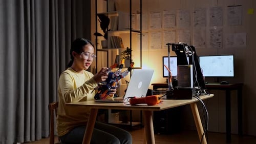 Young Woman Builds Robot at Table
