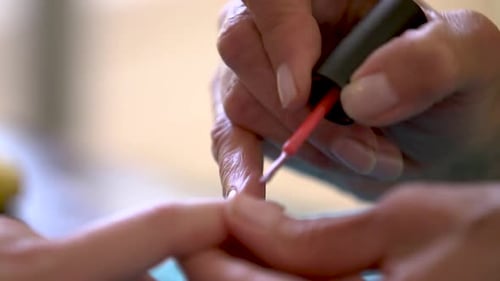 Adult Applies Bright Red Nail Polish to Fingernails