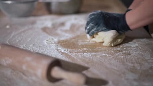 Weibliche Hände kneten Teig auf Holztisch, drinnen, Seitenansicht, Nahaufnahme, unkenntlich, Kaukasier