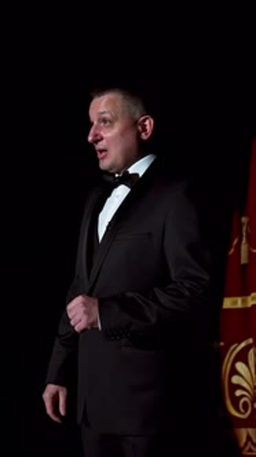 Announcer on a stage in theater. Bright round light on one person.
