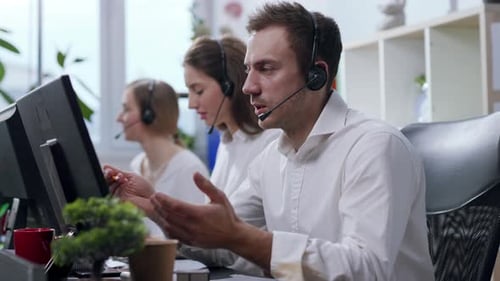 Portrait Tired Handsome Young Man Operator Taking with Customer Calls in Busy Call Center Use