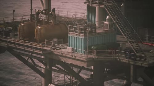 Oil Rig Equipment and Structures Against Coastal Backdrop at Dusk