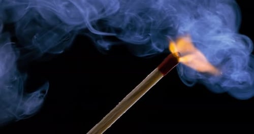 Burning matchstick close-up on a dark background. Shot on super slow motion camera 1000 fps.