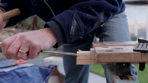 A man chiseling a wedge of wood.