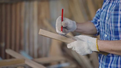 Asian senior carpenter using ruler to measuring wood board at the carpentry workshop