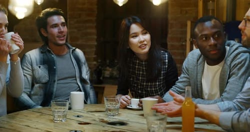 Slow motion of smiling friends having coffee at cafe and having fun with mobile cell phone. Shot i