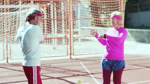 Senior Couple Exercising with Dumbbells on Sports Field