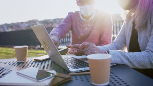 Businesspeople in city work on laptop with face masks during coronavirus pandemic