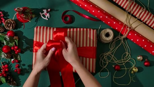 Hands Tying Ribbon on Christmas Present, Top View