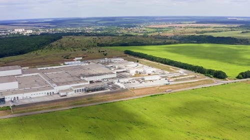 Moderna planta industrial en el campo. Gran fábrica entre una hermosa naturaleza verde.