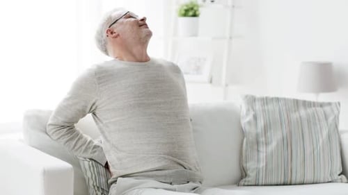 Senior Man Sitting on Couch with Back Pain