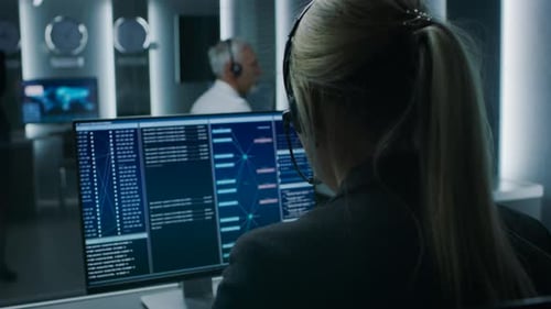 Back View of the Female Controller wearing Headset Working on Personal Computer, Monitoring Process
