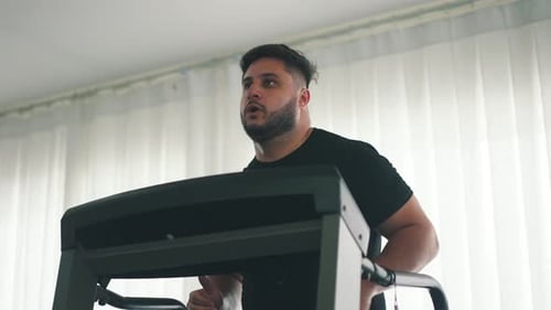 Jovem correndo focado treinando na esteira em câmera lenta