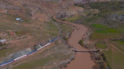 Vue aérienne d'un train serpentant dans une vallée accidentée et terreuse Turquie