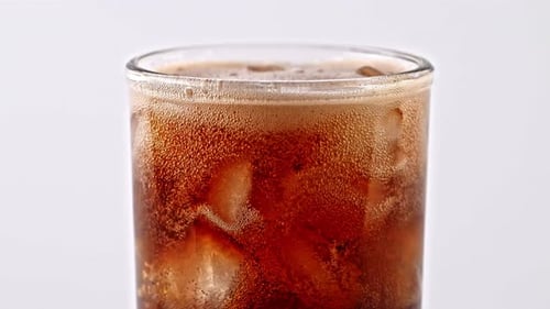 Soda Being Poured into Glass with Ice Cubes