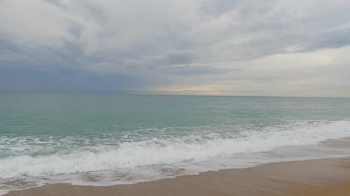Coarse sand beach sea wave in slow motion at 120fps 4k cloudy day turquoise water single sea waves B