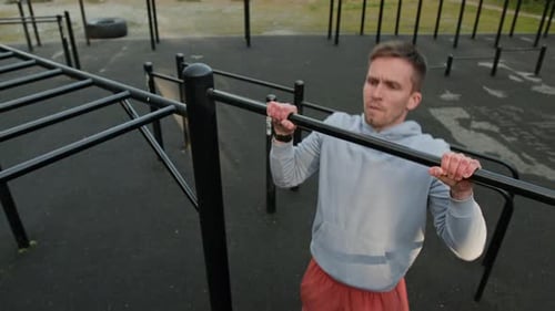 Young Man in Sportswear Performing Pull-Ups in Outdoor Training area