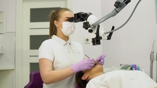 Dentist Using Microscope on Patient in Clinic