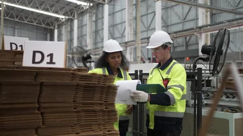 Factory Workers Examining Corrugated Cardboard in Manufacturing Plant