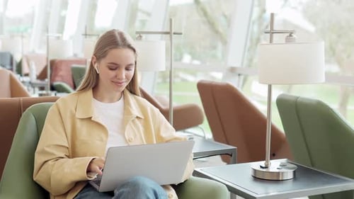 Teen Girl Student Looking at Laptop Sitting in Chair in University Elearning