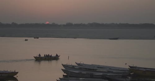 A wooden boat with passengers in Ganga River at sunrise in Varanasi, India.