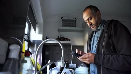 Man Uses Mobile Phone in Kitchen Indoors