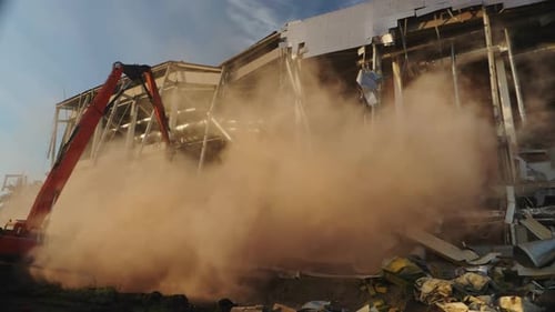 Excavatrice près d'un stade de hockey dans des nuages de poussière par temps ensoleillé