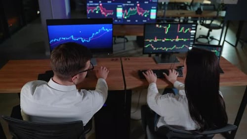 Vista traseira da equipe criativa de comerciantes que estão conversando em um escritório escuro com display