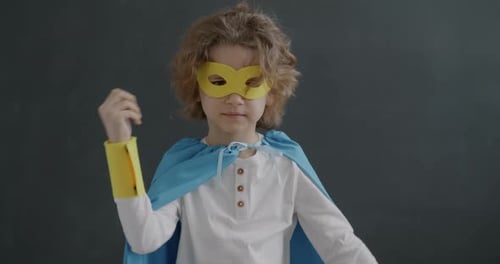 Young Child Dressed as Superhero Flexing Muscles
