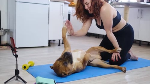 Woman Does High Five with Dog on Yoga Mat